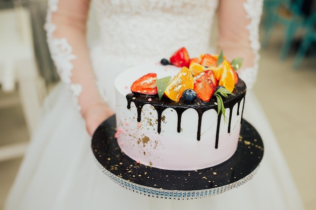 Novia sosteniendo un delicioso pastel de bodas