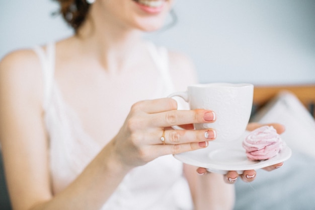 Novia sosteniendo una taza de café y galletas.