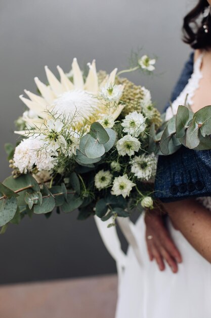 La novia sostiene un hermoso ramo de flores blancas de proteaxA