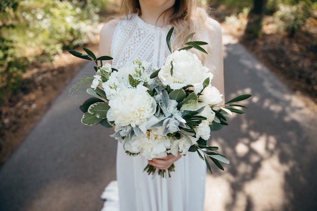 la novia sostiene un hermoso ramo de peonías en sus manos