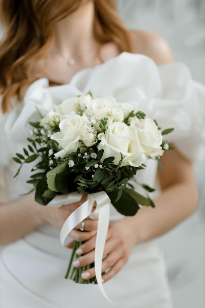 Foto la novia sostiene un hermoso ramo de rosas blancas