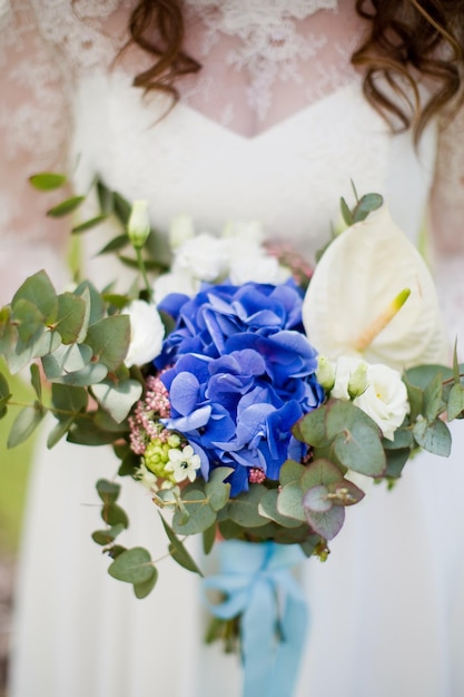 La novia sostiene un ramo de novia con hortensia azul, eucalipto, calla y eustoma.