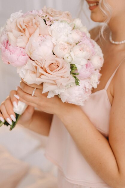 La novia sostiene un ramo de rosas en sus manos. Floristería de bodas.