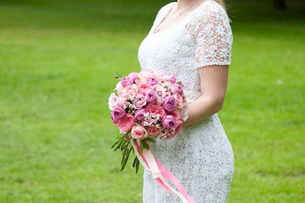 La novia sostiene en sus manos un accesorio de boda, un ramo de rosas.