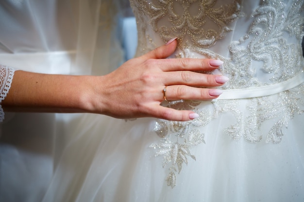 La novia sostiene en sus manos un hermoso vestido de novia