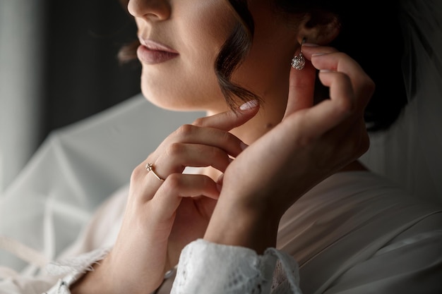 La novia tiene aretes en la mano el día de su boda. Joyas para unas vacaciones para los recién casados.