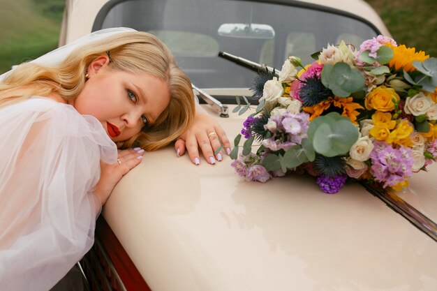 Foto novia de tiro medio posando con auto antiguo