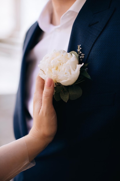 La novia toca la mano del boutonniere en la chaqueta de la novia.