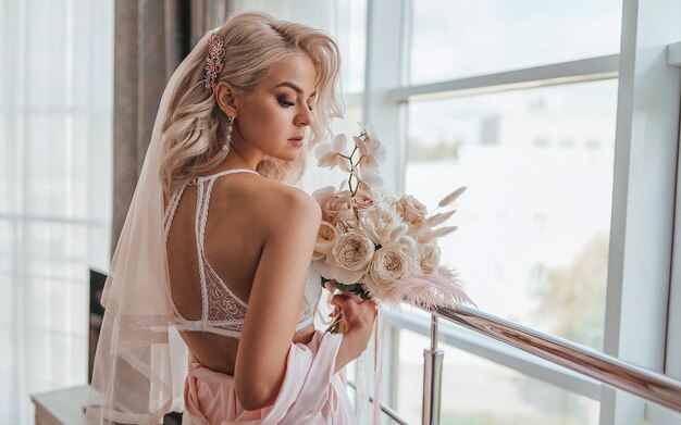 una novia con un velo y flores frente a una ventana