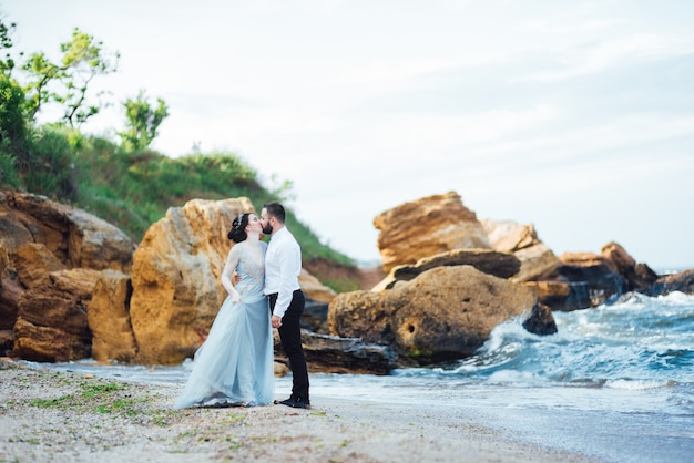 novia en un vestido azul caminar a lo largo de la orilla del mar