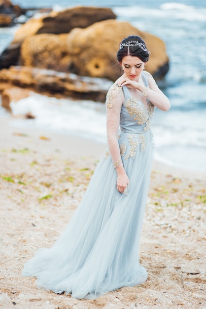 Foto novia con un vestido azul claro caminando por el océano