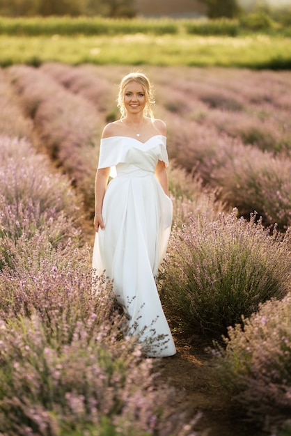 La novia con un vestido blanco camina sobre el campo de lavanda