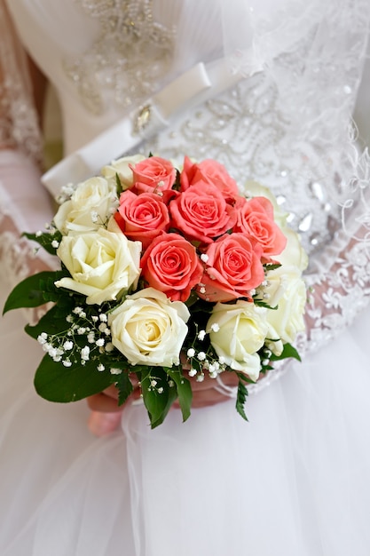 La novia con un vestido blanco en una ceremonia de boda con un ramo de rosas.