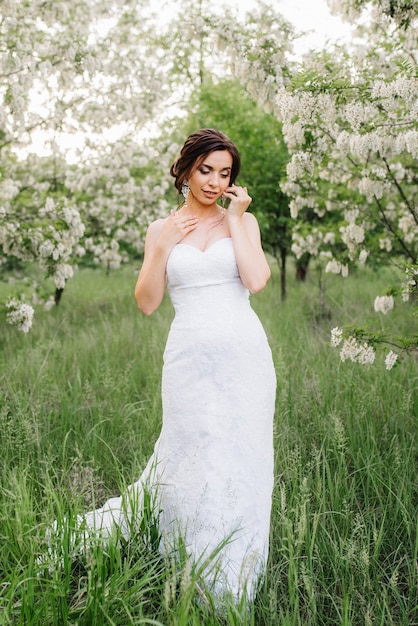 Novia con un vestido blanco con un gran ramo de primavera en un bosque verde