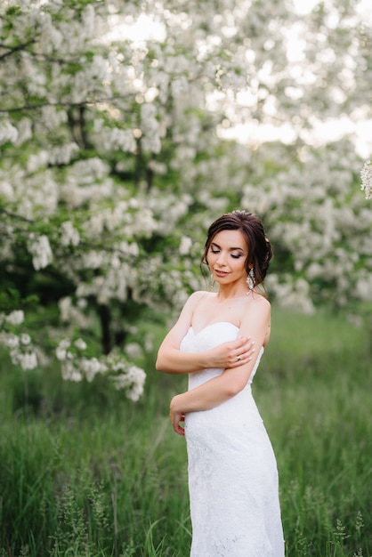 Novia con un vestido blanco con un gran ramo de primavera en un bosque verde