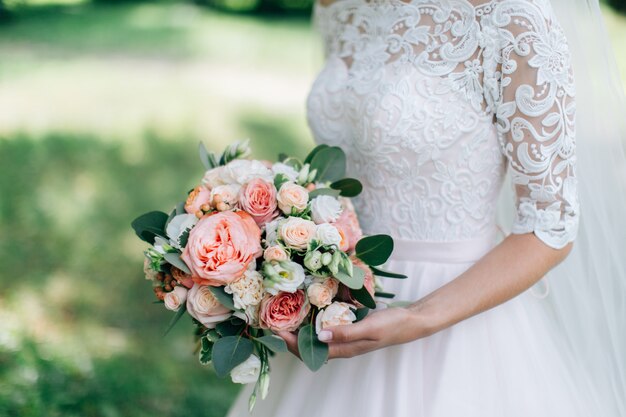 Novia en vestido blanco con hermoso ramo. Fondo verde