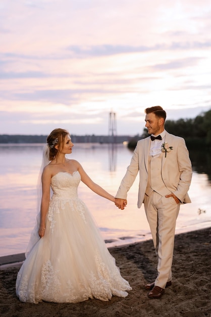 Novia con un vestido blanco hinchado y el novio en t en la orilla del río