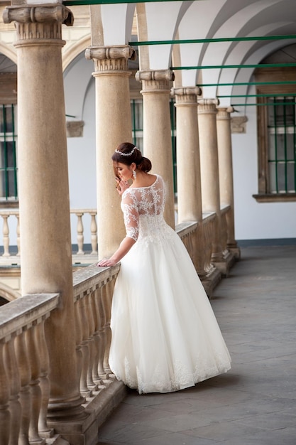 Una novia con un vestido blanco mira desde un balcón.