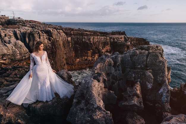 Novia en vestido blanco de moda cerró los ojos contra el bac