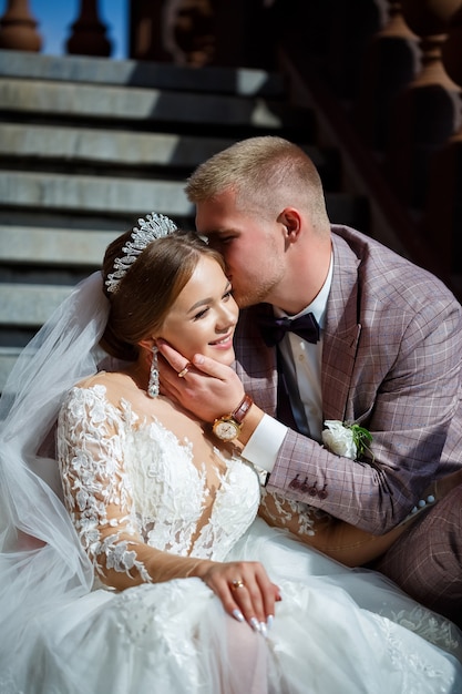 La novia en vestido blanco y el novio en trajes se abrazan en los pasos