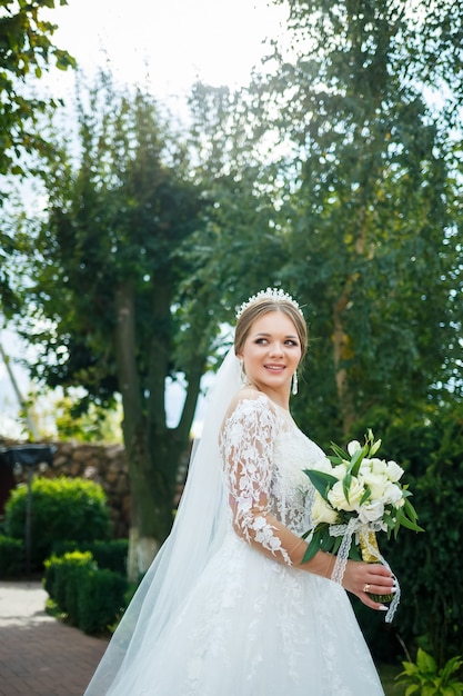 Novia con un vestido blanco con un ramo en las manos y una corona en la cabeza.