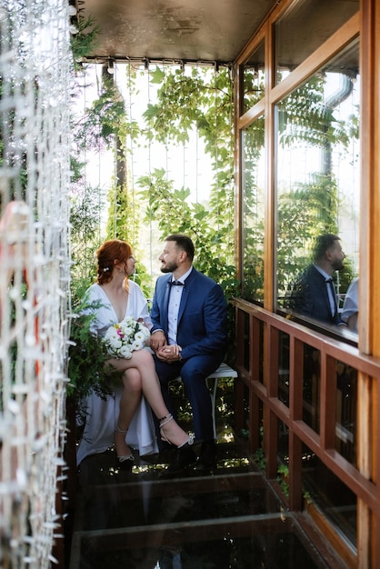 La novia con un vestido blanco con un ramo y el novio con un traje azul.