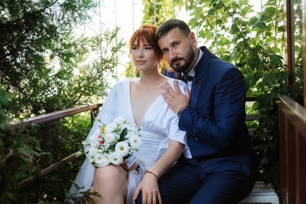 La novia con un vestido blanco con un ramo y el novio con un traje azul.