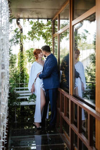 La novia con un vestido blanco con un ramo y el novio con un traje azul.