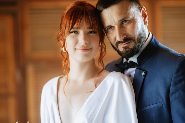 La novia con un vestido blanco con un ramo y el novio con un traje azul.