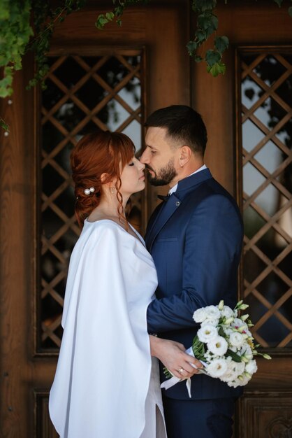 La novia con un vestido blanco con un ramo y el novio con un traje azul.