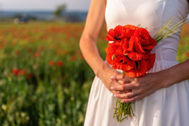 Novia con un vestido blanco sosteniendo un ramo de flores de amapola cálida puesta de sol en el fondo de la