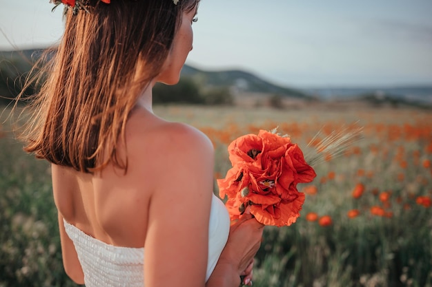 Novia con un vestido blanco sosteniendo un ramo de flores de amapola cálida puesta de sol en el fondo de la