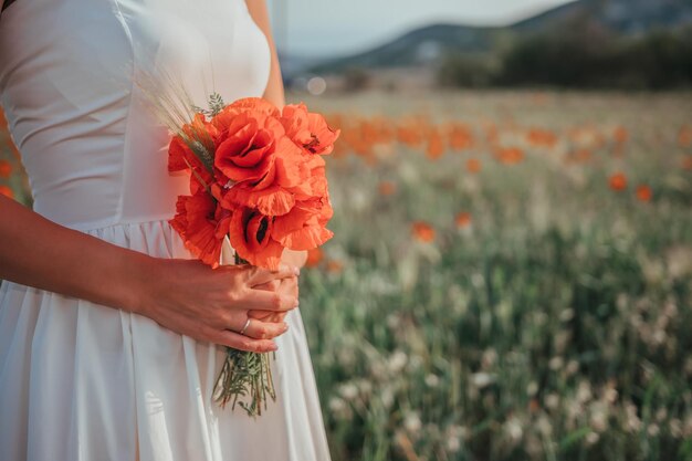 Novia con un vestido blanco sosteniendo un ramo de flores de amapola cálida puesta de sol en el fondo de la