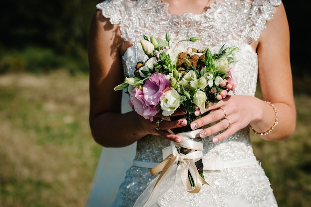 Novia con un vestido blanco sosteniendo un ramo de flores rosas