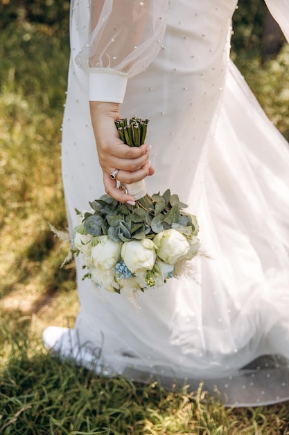 La novia en un vestido blanco sostiene hermosas flores en sus manos