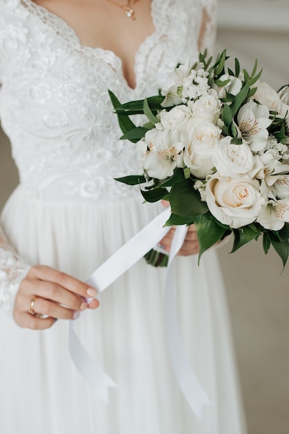 Novia en vestido blanco tiene su ramo de novia