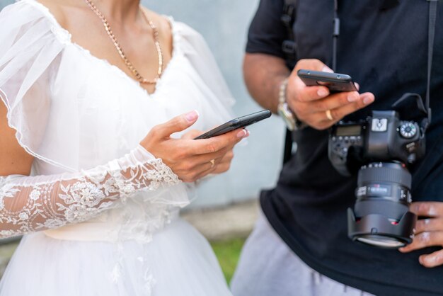 La novia con un vestido blanco tiene un teléfono inteligente en la mano.