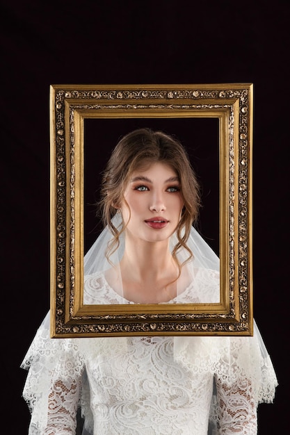 Novia con vestido blanco tomando un cuadro frente a sus rostros