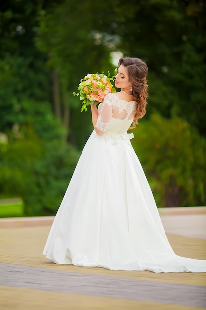 Novia con un vestido largo blanco con un ramo de pie