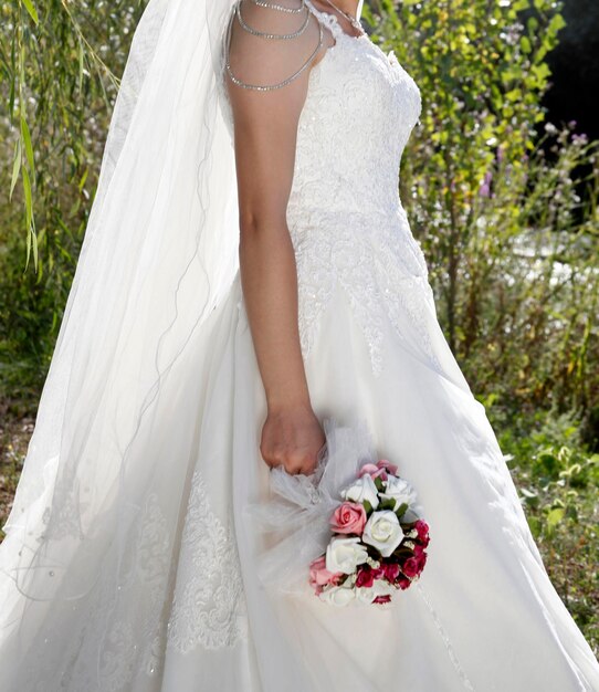 Novia en vestido de novia blanco con bordados de encaje Un ramo de flores en manos de la novia