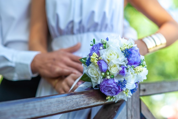 La novia con un vestido de novia blanco sostiene un ramo de novia La novia tiene un anillo de bodas en la mano