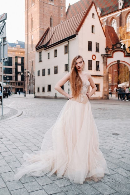 Una novia con un vestido de novia con el pelo largo en el casco antiguo de Wroclaw.