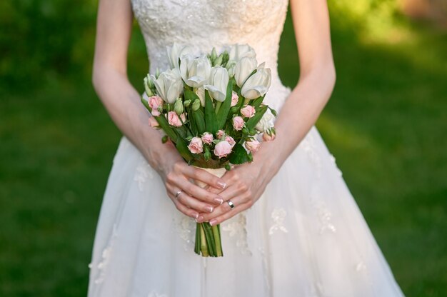 Novia con vestido de novia y ramo de flores en el día de su boda