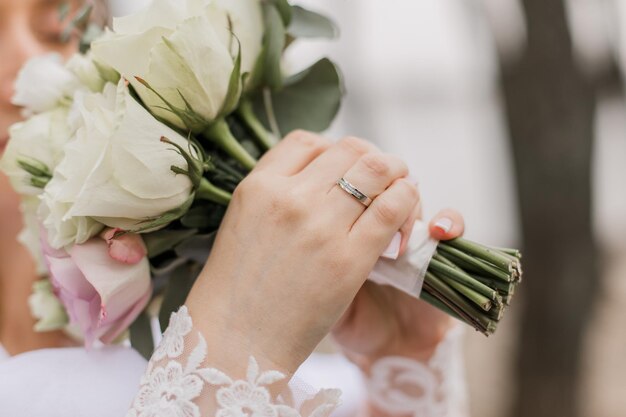 La novia con un vestido de novia sostiene un ramo de flores en sus manos.