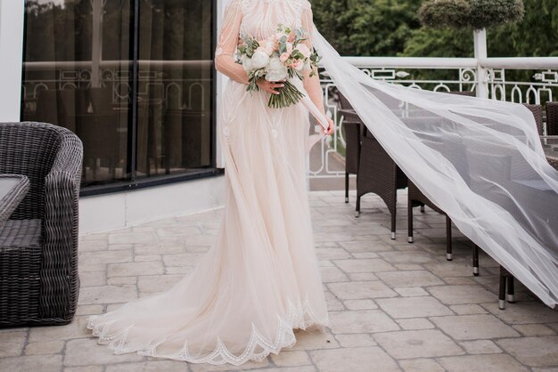 La novia con un vestido de novia sostiene un ramo.