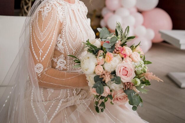 La novia con un vestido de novia sostiene un ramo.