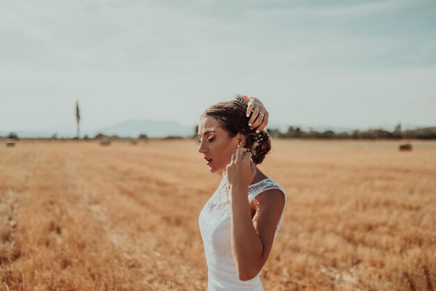 La novia con un vestido posa en un gran campo al atardecer. foto de alta calidad