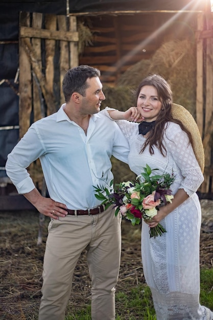 La novia con un vestido con un ramo se pone un sombrero y se ríe Boda rústica al estilo boho en el rancho