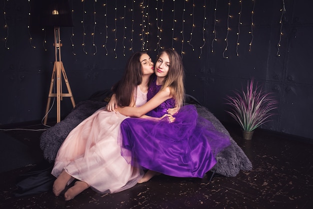 Novias alegres Dos chicas de pelo largo en vestidos de color rosa y morado