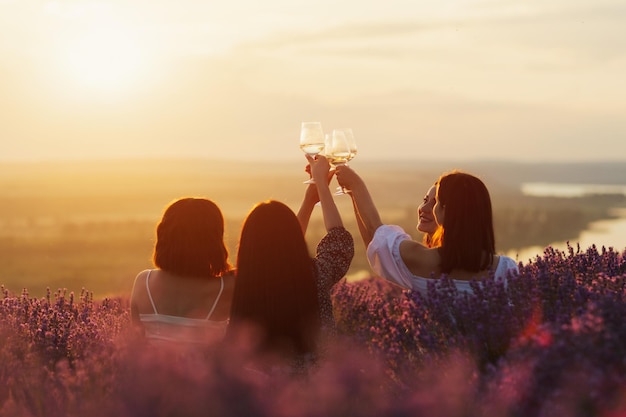 novias bebiendo vino al atardecer de verano en el campo de lavanda